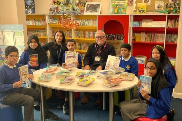 Trustee Graham sitting at a table alongside school pupils with books