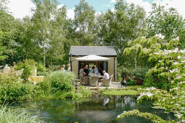 The summerhouse, with outdoor table and chairs set next to the pond