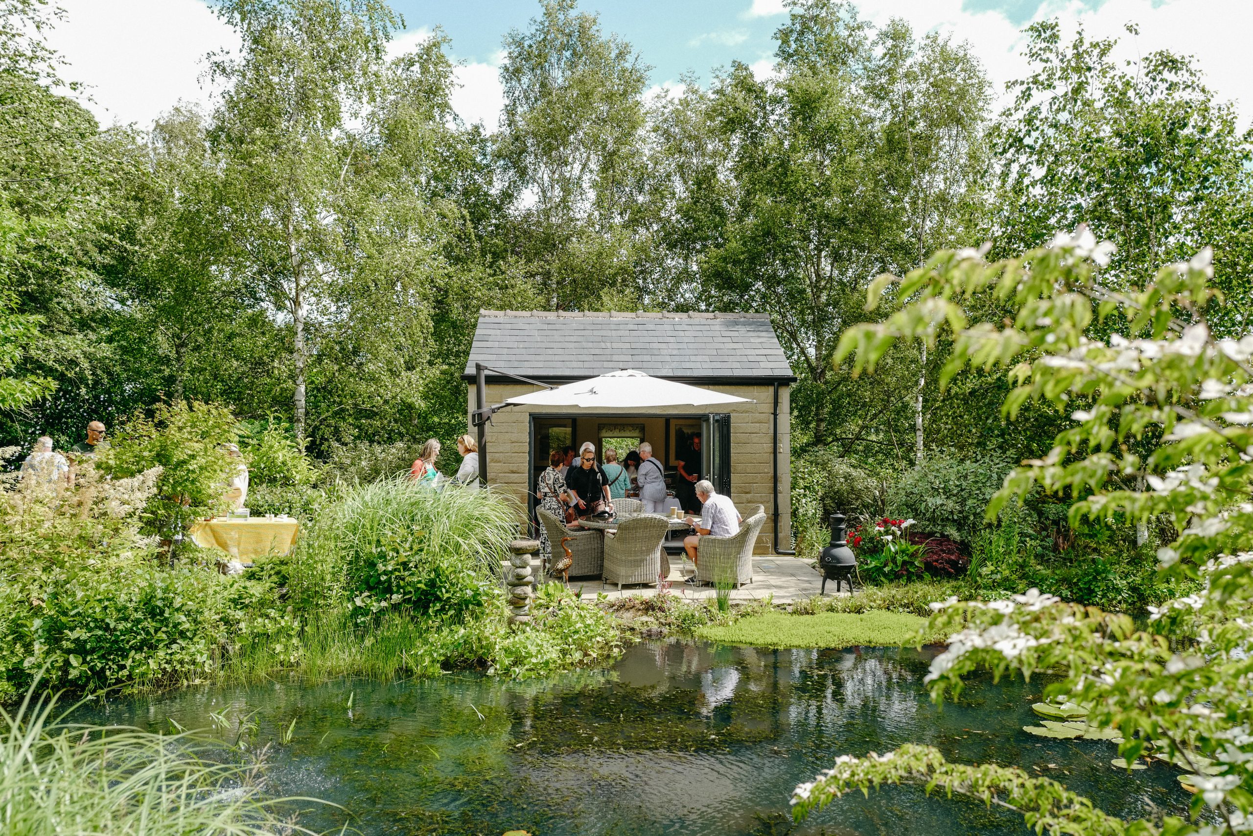 The summerhouse, with outdoor table and chairs set next to the pond